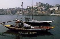 Traditional 'moliceiros' boats carrying barrels of port off the coast of El Douro, Portugal. ^^^The region cultivates more than eighty grape varieties and uses half its grapes to produce port.