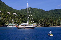 Yacht anchored in a Caribbean harbour with a man in a kayak in the foreground.