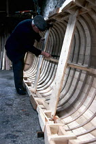 Craftsman building a curragh, a traditional sailing boat native to Ireland. Curraghs are made of leather or tarred canvas stretched over a wooden framework.