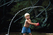 Young boy throwing water from a bucket through the air. Model released.
