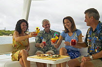Group of people drinking cocktails aboard a cruising catamaran, Seychelles.