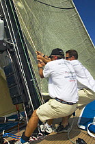 Crew pumping the halyard aboard a race yacht.