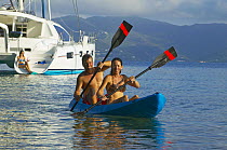 Couple kayaking from their cruising catamaran, Seychelles.