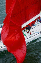 Crew lowering the spinnaker between the boom and mainsail foot.