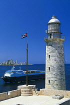 The lighthouse at the entrance to Havana Harbour with a ship cruising past, Cuba.