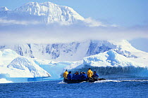 Tourists in a zodiac RIB in front of icebergs with low cloud, Antarctica.