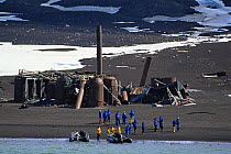 Tenders on the shore with visitors from a cruise ship exploring the volcanic crater of Deception Island, Antarctic Peninsula. Half buried buildings and machinery remain after a landslide on the island...