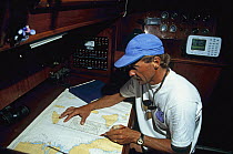 Skipper reading the chart in navigation station on yacht.