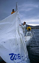 Yacht crew pulling the mainsail down a broken mast.