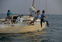 Crew balancing on the end of the boom in an attempt to refloat the yacht which has run aground.