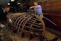 A group of boat builders working on the skeleton of a wooden boat at the International Yacht Restoration School (IYRS), Newport, Rhode Island, USA.