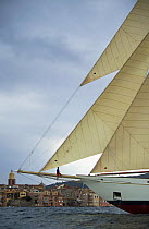 A crew member sitting on the bowsprit of classic wooden boat "Adix" during the Nioulargue sailing festival, St Tropez, France. Property Released.