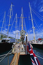 Tall masts and stern detail of the classic yacht "Mariette" with the ensign and passarelle out, moored next to J-Class "Velsheda" in a harbour.