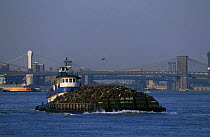 A waste-barge under tow beside Newport Bridge, Newport, Rhode Island, USA.