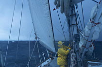 A crew member tending to the lines aboard 'Sariyah', in strong onshore winds and a heavy swell, heading along the coast of Chile towards Cape Horn.