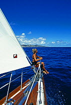 A female crew member sitting on the bow of "Realite", St Maarten, Caribbean. Model and Property Released.
