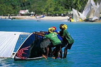 Locals trying to right a traditional work boat that has capsized, Grenada Sailing Festival, Grenada, Caribbean.