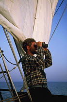 Crew member on board "Gazela" looking through binoculars, on watch at the Tall Ship event Sail New York to Boston, USA.