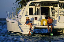 People snorkeling off the back of a cruising catamaran, Belize.
