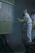Spray painting the hull of a boat in the spray painting booth at Hinckley, Rhode Island, USA.