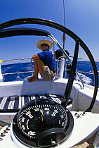 Man sitting on the stern of a cruising yacht heading northwards.