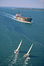 Two yachts sailing close hauled into the path of an oncoming rusty tanker.