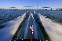 The wake of a motorboat with Newport Bridge in the background, Rhode Island, USA.