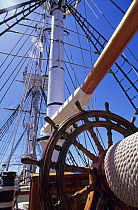 Wheel on board Tall Ship "Bounty", looking aft up to the rigging.