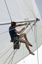 Yacht crew member rigging a second foresail to the spinnaker pole.