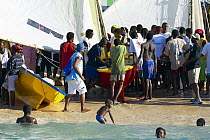 Crowd on the shore with traditional boats and children swimming in the sea, Grenada Sailing Festival 2005, Grenada, Caribbean.