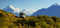 Campervan parked in a layby with snowcapped mountains beyond, South Island, New Zealand.