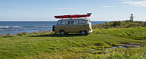 Canoe on the roof of a VW Camper Van parked up by the sea, South Island, New Zealand.