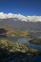 View into a fjord with a town below and mountains and clouds in the distance, South Island, New Zealand.