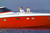 Two women sitting on the foredeck of high performance motoryacht "Azzurra 63'", as it cruises off Procida Island, Italy. The luxury yacht was built by Naples-based specialist Cantieri di Baia. It is 1...