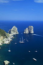 Yachts anchored off Faraglioni, a group of rocks on the jagged coast of Capri, Bay of Naples, Italy. This view is from Monte Solaro.