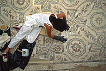Woman painstakingly restoring mosaics at the Villa Romana del Casale, Piazza Armerina, Sicily, Italy. The Villa Romana del Casale is a UNESCO World Heritage Site and has the richest, largest and most...