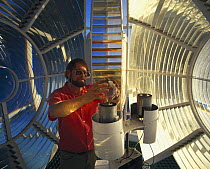 Changing the bulb inside the lens of a lighthouse.
