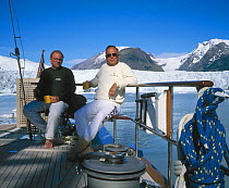 Owner of yacht "Sariyah" sitting on deck with a friend in the icy reaches of Chilean Patagonia.