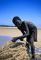 Boy with coil of rope on the beach at Benguerra Island, Mozambique.