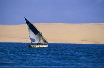 A local sailing boat (dhow) with sand dunes behind, Benguerra Island (the second largest island in the Bazaruto archipelago), Mozambique