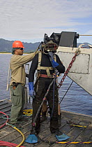 Commercial hard hat diver preparing for a dive, Oahu, Hawaii. Model released.