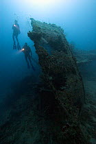 Scuba divers use torches to explore a wreck in the sea off Palau, Micronesia. Model released.