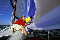 Crew gathering in the lowered spinnaker aboard a racing yacht.
