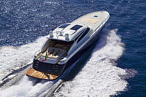 Two women sunbathing on the sundeck of a Continential 80 motor yacht, designed and built at Cantieri CNM, cruising the coast of Cannes, France.