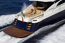 Two women sunbathing on the sundeck of a Continential 80 motor yacht, designed and built at Cantieri CNM, cruising the coast of Cannes, France.