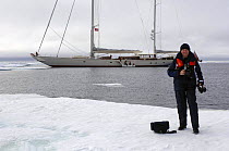 Crew member of Superyacht "Adele" stands on the frozen waters of Spitsbergen (also know as Svalbard) in Norway. ^^^ The yacht can be seen in the background. She is 180 foot Andre Hoek design, built b...