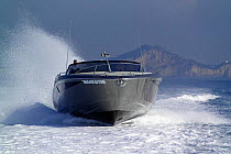 Power boat cruising at speed along the coast. Motorboat "One", Cantieri di Baia, off the coast of Baia, Naples, Italy.