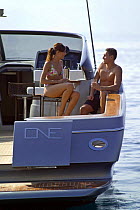 Couple sitting on bar stools on the deck of a power boat. Motorboat "One", Cantieri di Baia, off the coast of Baia, Naples, Italy.