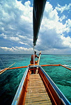 Man paddling a Banca, a typical fishing boat of this area, over coral reefs at Balicasag Island (Bohol), Philippines.