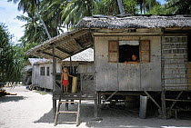 Boy standing on verandah of his hut in a small fishing village on a little island near Dakak Island, Philippines.
